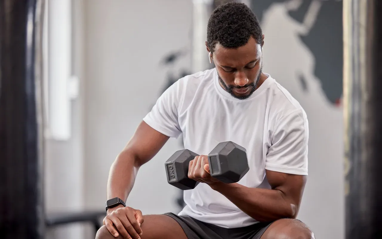 Homme noir qui se muscle les biceps assis