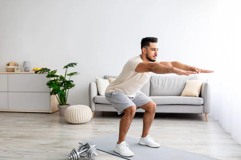 Jeune homme faisant des squats musculation sans matériel